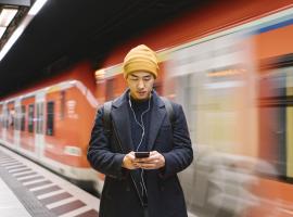 person looking at phone standing on train platform 