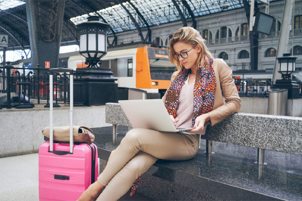 Woman working on her laptop next to her suitcase