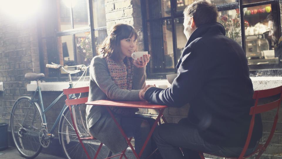woman and man sitting outside at red table