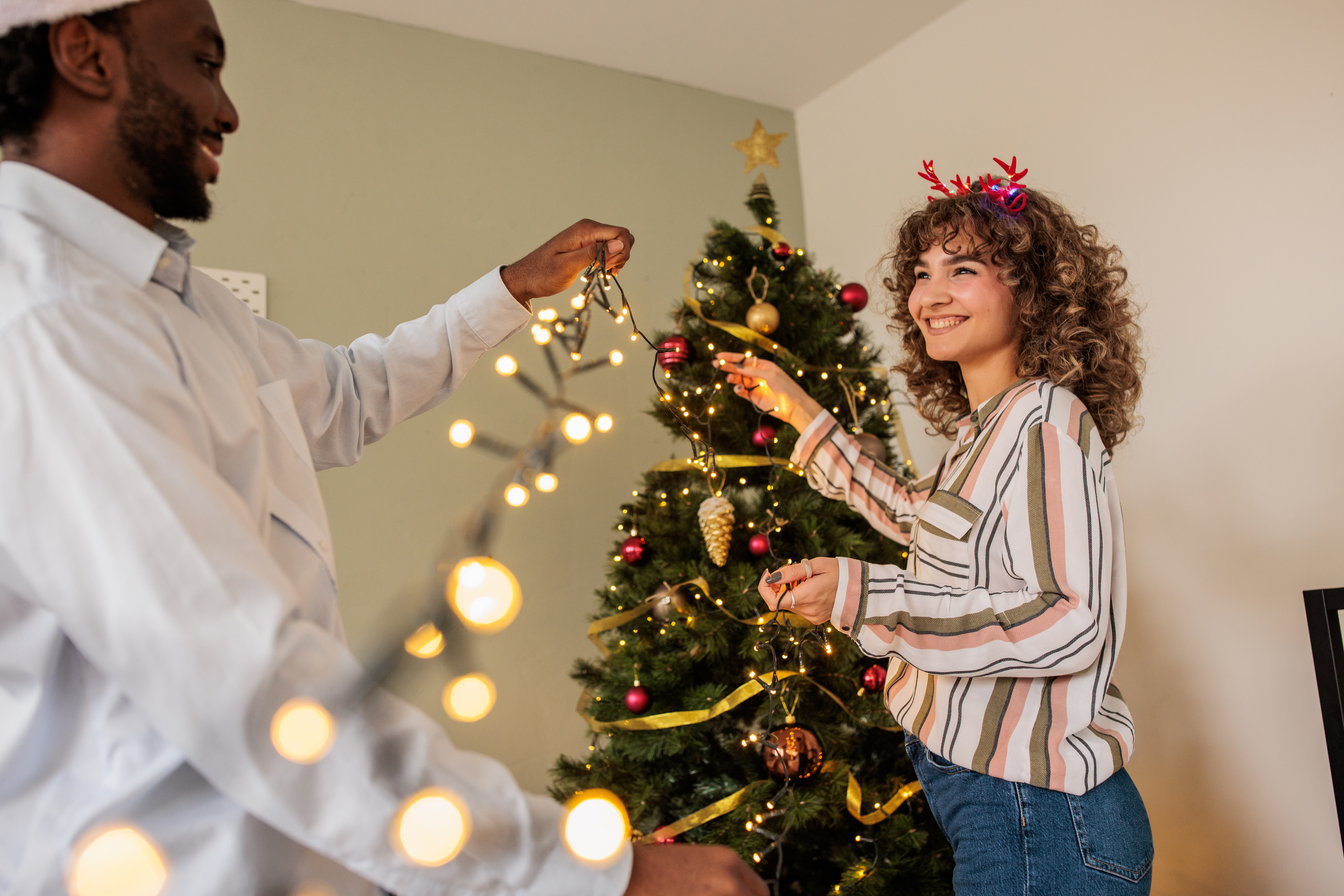 two people decorating Christmas tree