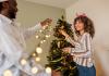 two people decorating Christmas tree